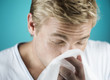 A young man blowing his nose