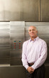 Male restaurant manager standing in commercial kitchen, smiling, portrait