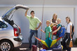 Photo: Family loading camping equipment into parked car boot on driveway, boy (8-10) holding fishing rod and kite, smiling, side view, portrait Family loading camping equipment into parked car boot on driveway, boy (8-10) holding fishing rod and kite, smiling, side view, portrait