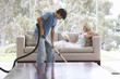 A young boy vacuuming whilst his mother relaxes