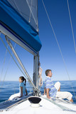 Photo: Father and daughter (8-10) sitting back to back at bow of sailing boat, smiling, profile Father and daughter (8-10) sitting back to back at bow of sailing boat, smiling, profile
