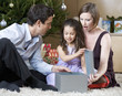 A couple and their young daughter opening Christmas presents