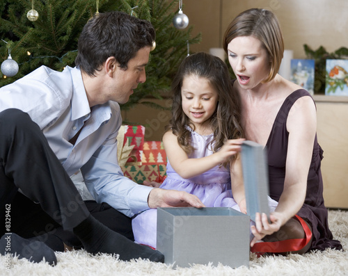 Photo: A couple and their young daughter opening Christmas presents A couple and their young daughter opening Christmas presents