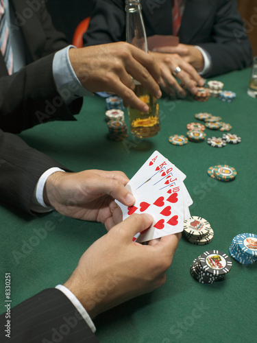 Photo: Detail of man holding playing cards at poker game Detail of man holding playing cards at poker game
