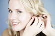 A young woman putting on earrings