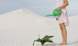 A woman watering a plant in the sand