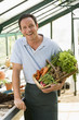 Man in greenhouse holding basket of vegetables smiling