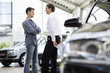 A young man talking to a car salesman