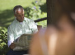 Man sitting in a garden reading a newspaper