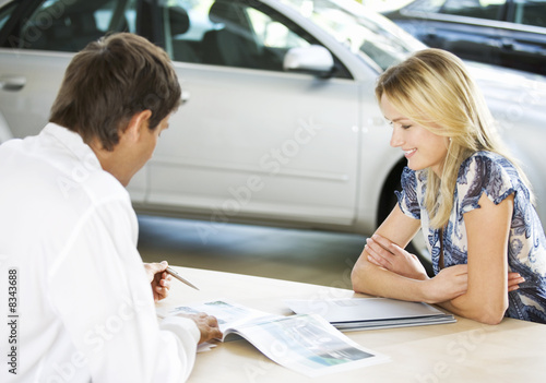 Foto: A young woman buying a new car A young woman buying a new car