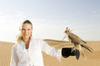 A woman standing in the desert with a hawk