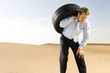 A man standing in the desert with a tyre