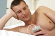 Young man in bed listening to music