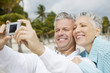 Foto: A senior couple on a beach taking a picture with a digital camera A senior couple on a beach taking a picture with a digital camera