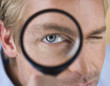 A young man looking through a magnifying glass