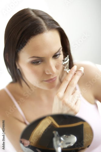 Foto: Young woman curling eyelashes Young woman curling eyelashes