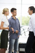 A young couple talking to a car salesman