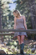 A young woman standing on a wooden bridge in a forest