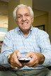 An elderly man using a TV remote control