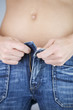 A young woman putting on jeans