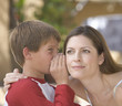 A young boy whispering to his mother