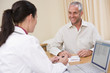 Doctor with laptop and man in doctor's office smiling