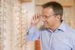 Man trying on eyeglasses at optometrists smiling