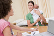 Doctor with laptop and woman in doctor's office holding baby