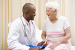 Doctor giving checkup to woman in exam room smiling