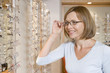 Woman trying on eyeglasses at optometrists smiling
