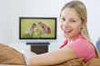 Woman in living room watching television smiling