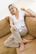 Woman in living room holding remote control smiling