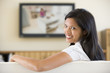 Woman in living room watching television smiling