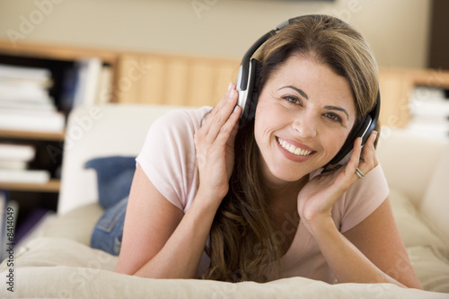 Woman in living room listening to headphones smiling