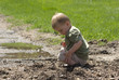 Toddler playing in mud after rainfall on park trail