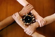 Four arms locked together at the wrists with a pencil cup