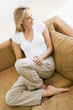 Woman in living room listening to MP3 player smiling Woman in living room listening to MP3 player smiling