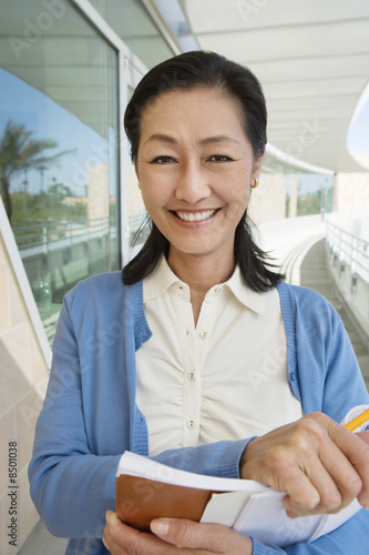 Photo: Woman holding book at school, smiling, portrait Woman holding book at school, smiling, portrait