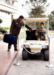 Bellboy driving hotel cart to deliver luggage to doorman
