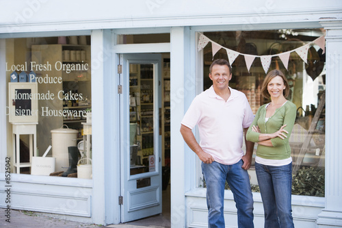 Photo: Couple standing in front of organic food store smiling Couple standing in front of organic food store smiling
