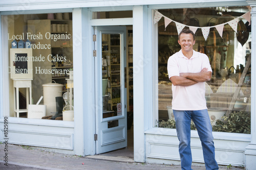 Photo: Man standing in front of organic food store smiling Man standing in front of organic food store smiling