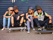 Happy couples sitting on street looking on cellphone