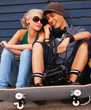 Happy couple sitting on street talking on cellphone