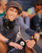 Young teen sitting holding skateboard friends in the background