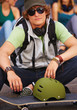 Portrait of a young boy sitting by skateboard