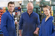 Photo: Three machinists in workspace by machine talking Three machinists in workspace by machine talking