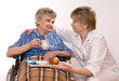 Health care worker and elderly woman in wheelchair needs help