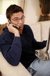 Young man reading newspaper and talking on cell phone