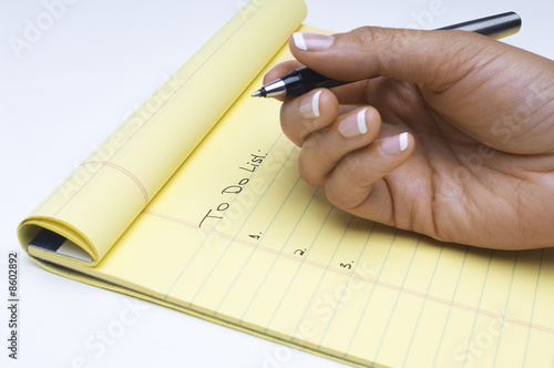 Photo: Woman writing list of tasks to do, close-up of hand Woman writing list of tasks to do, close-up of hand