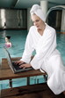 Woman on computer next  to a swimming pool